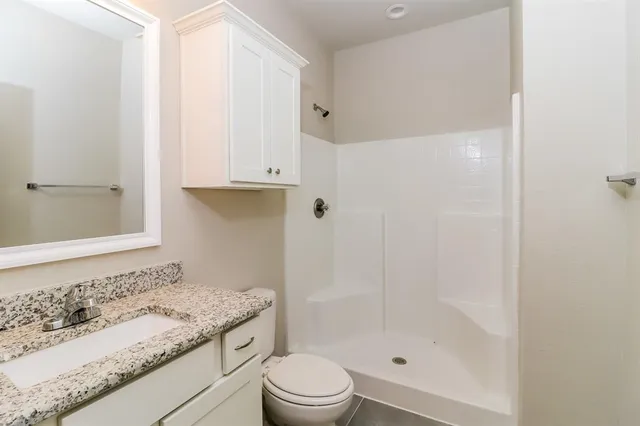 a bathroom with a granite countertop sink a toilet and shower