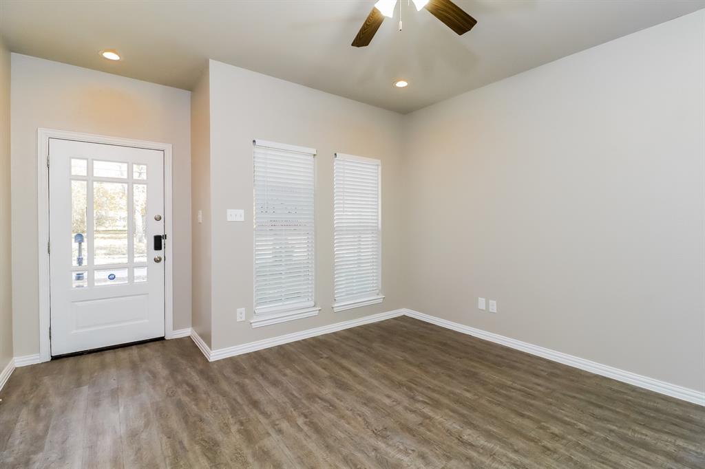 206 Perry Avenue Waxahachie, TX 75165 - Photo 4 of 15 an empty room with wooden floor chandelier fan and windows