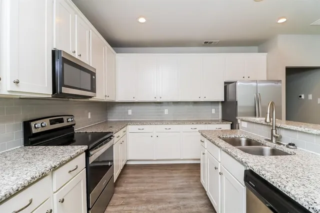 a kitchen with granite countertop a sink dishwasher stove and oven with wooden floor