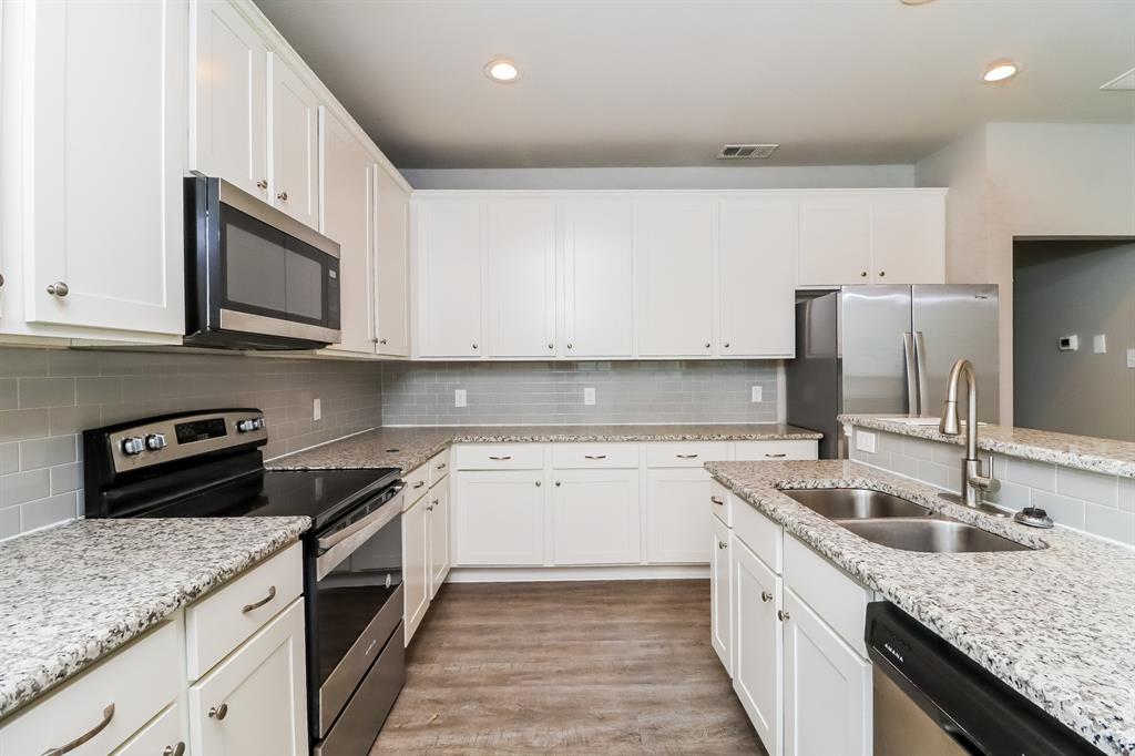 206 Perry Avenue Waxahachie, TX 75165 - Photo 5 of 15 a kitchen with granite countertop a sink dishwasher stove and oven with wooden floor