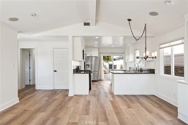 a kitchen with stainless steel appliances granite countertop a stove a sink and white cabinets with wooden floor