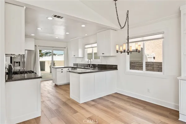 a kitchen with stainless steel appliances granite countertop a refrigerator a sink dishwasher a oven with white cabinets and wooden floor