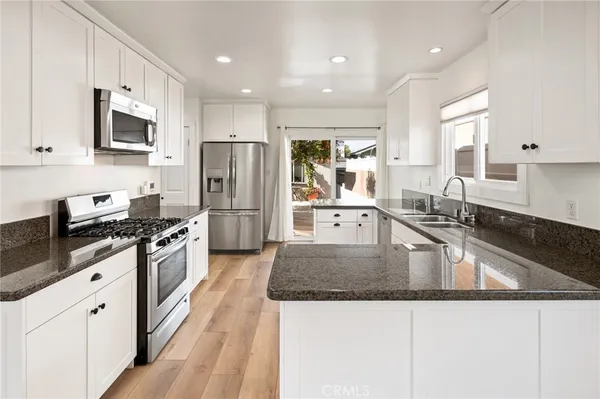 a kitchen with granite countertop a sink stove and refrigerator