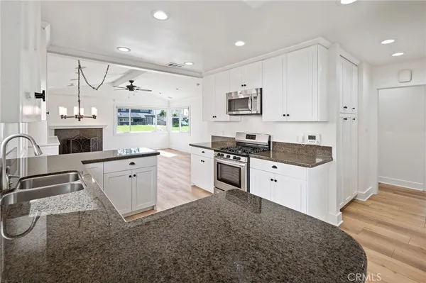 a kitchen with granite countertop a stove top oven a sink a counter space and cabinets