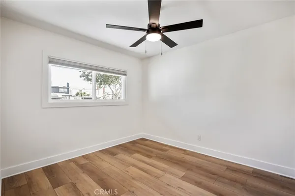 an empty room with wooden floor and a ceiling fan