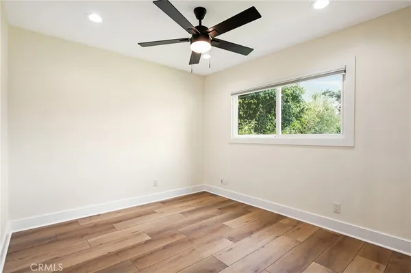 a view of empty room with wooden floor and fan