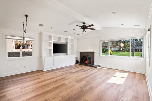 a view of an empty room with wooden floor fireplace and a window