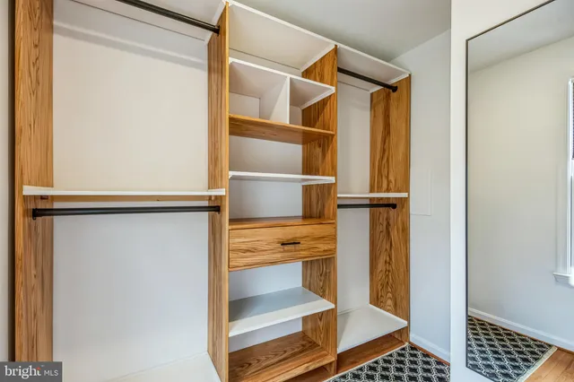 a walk in closet with wooden floor