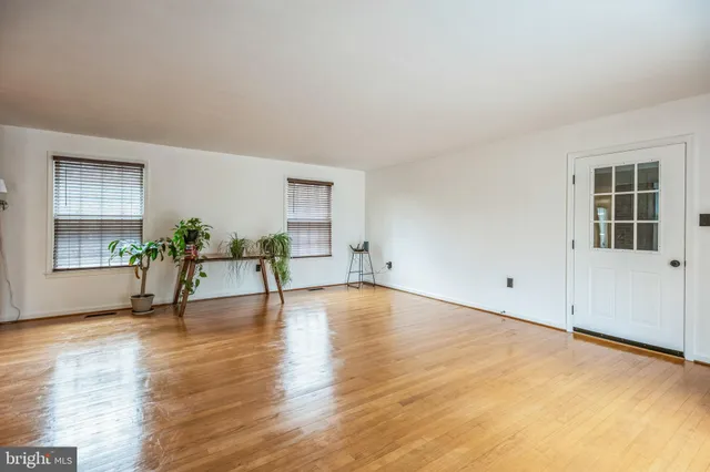 a view of an empty room with window and wooden floor