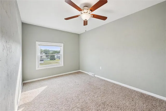 an empty room with a window and a fan
