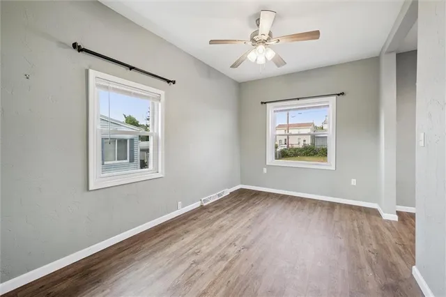 an empty room with wooden floor and windows