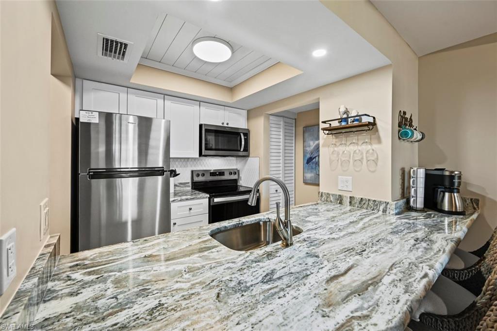 200 Lenell Road, Unit 215 Fort Myers Beach, FL 33931 - Photo 4 of 29 a kitchen with granite countertop a refrigerator stove microwave and sink