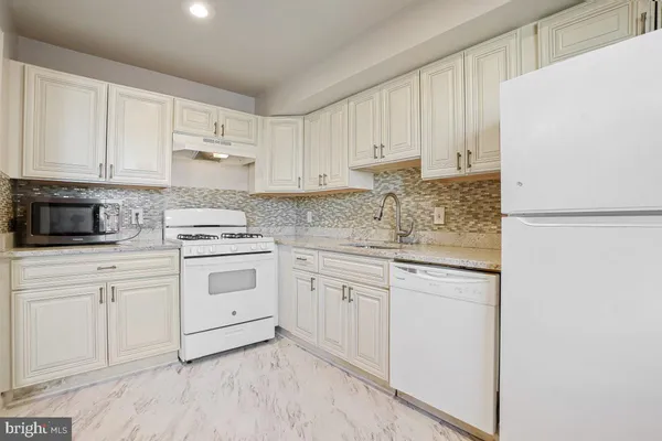 a kitchen with granite countertop white cabinets and white appliances