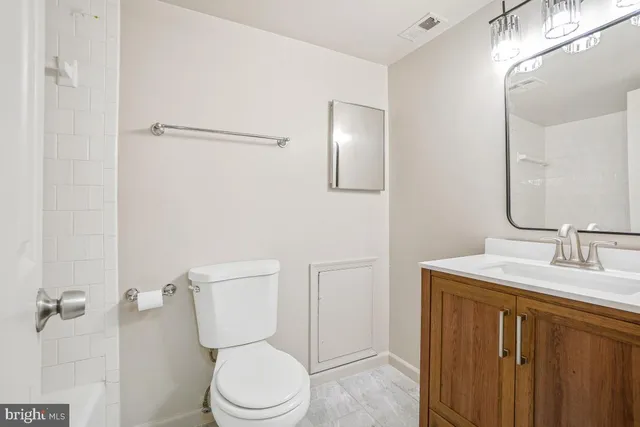 a bathroom with a toilet sink vanity and mirror