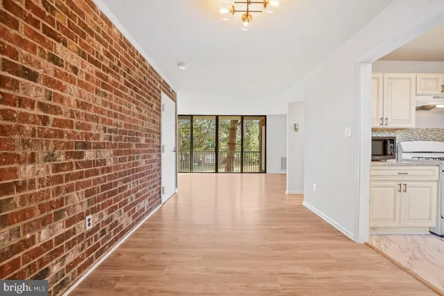a view of a hallway with wooden floor and a bathroom