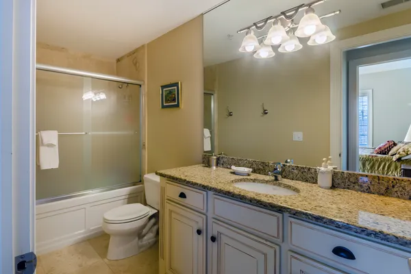 a bathroom with a granite countertop sink a toilet and shower