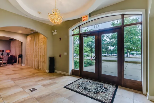 a view of a hallway with a chandelier and glass door
