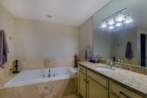 a bathroom with a tub sink and mirror