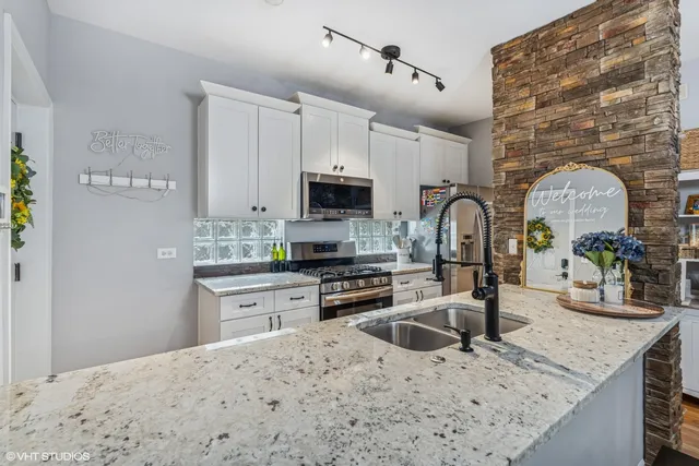 a kitchen with granite countertop a stove a sink and a microwave