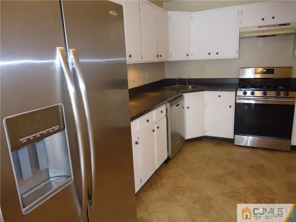 a kitchen with granite countertop a refrigerator and a stove top oven
