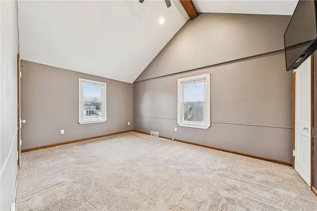 an empty room with windows and refrigerator