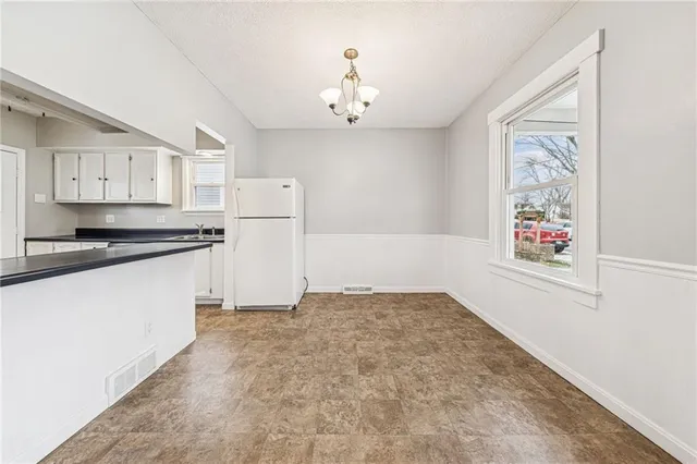 a view of kitchen with refrigerator and white cabinets