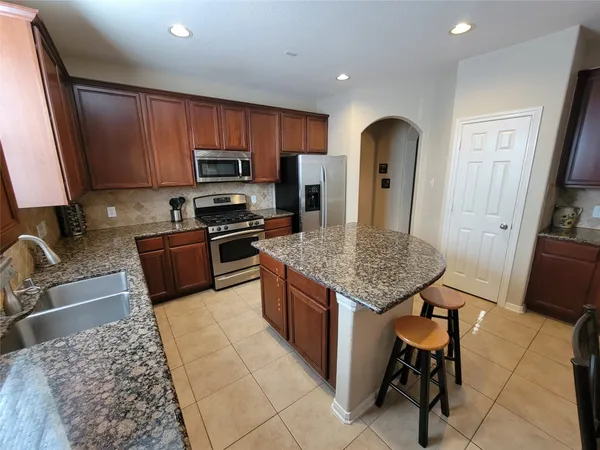 a kitchen with stainless steel appliances granite countertop a stove top oven a sink dishwasher a dining table and chairs with wooden floor