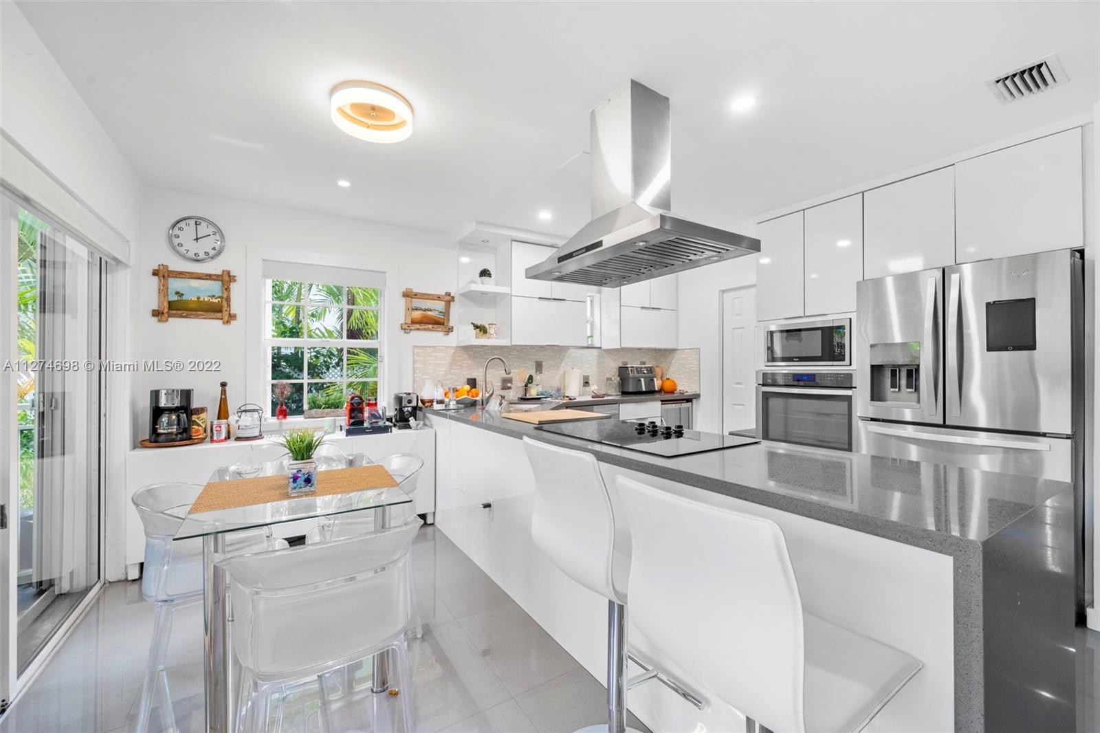 442 Fernwood Road Key Biscayne, FL 33149 - Photo 8 of 33 a kitchen with white cabinets and stainless steel appliances