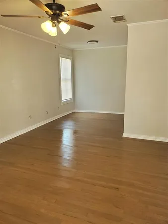 a view of an empty room with wooden floor and a window