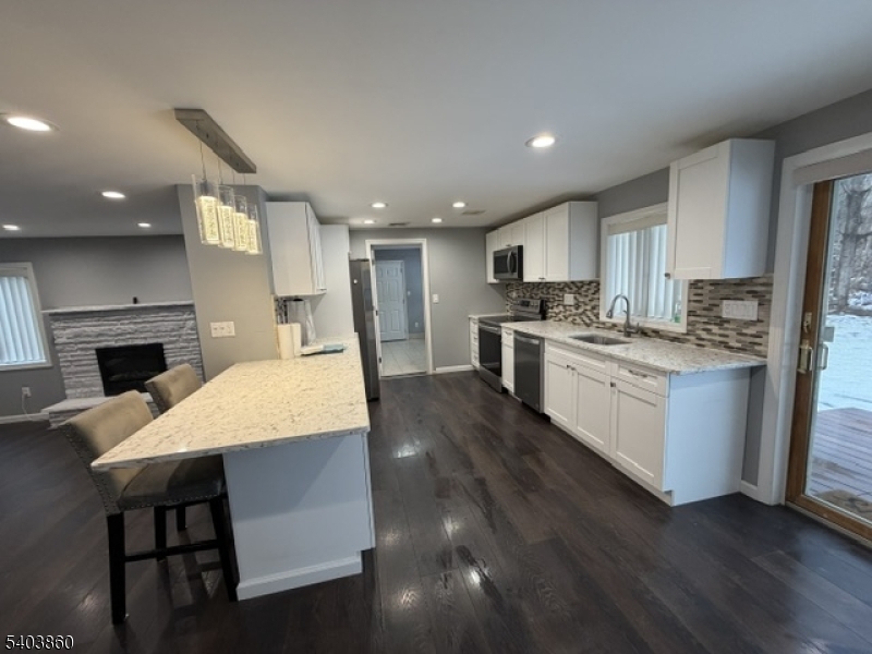 36 Wawayanda Road Vernon, NJ 07422 - Photo 34 of 34 a large kitchen with kitchen island a stove a sink a refrigerator and a dining table with wooden floor