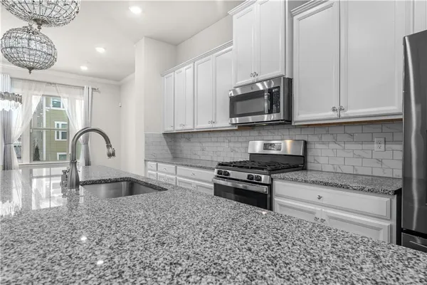 a kitchen with stainless steel appliances granite countertop a stove a sink and a microwave
