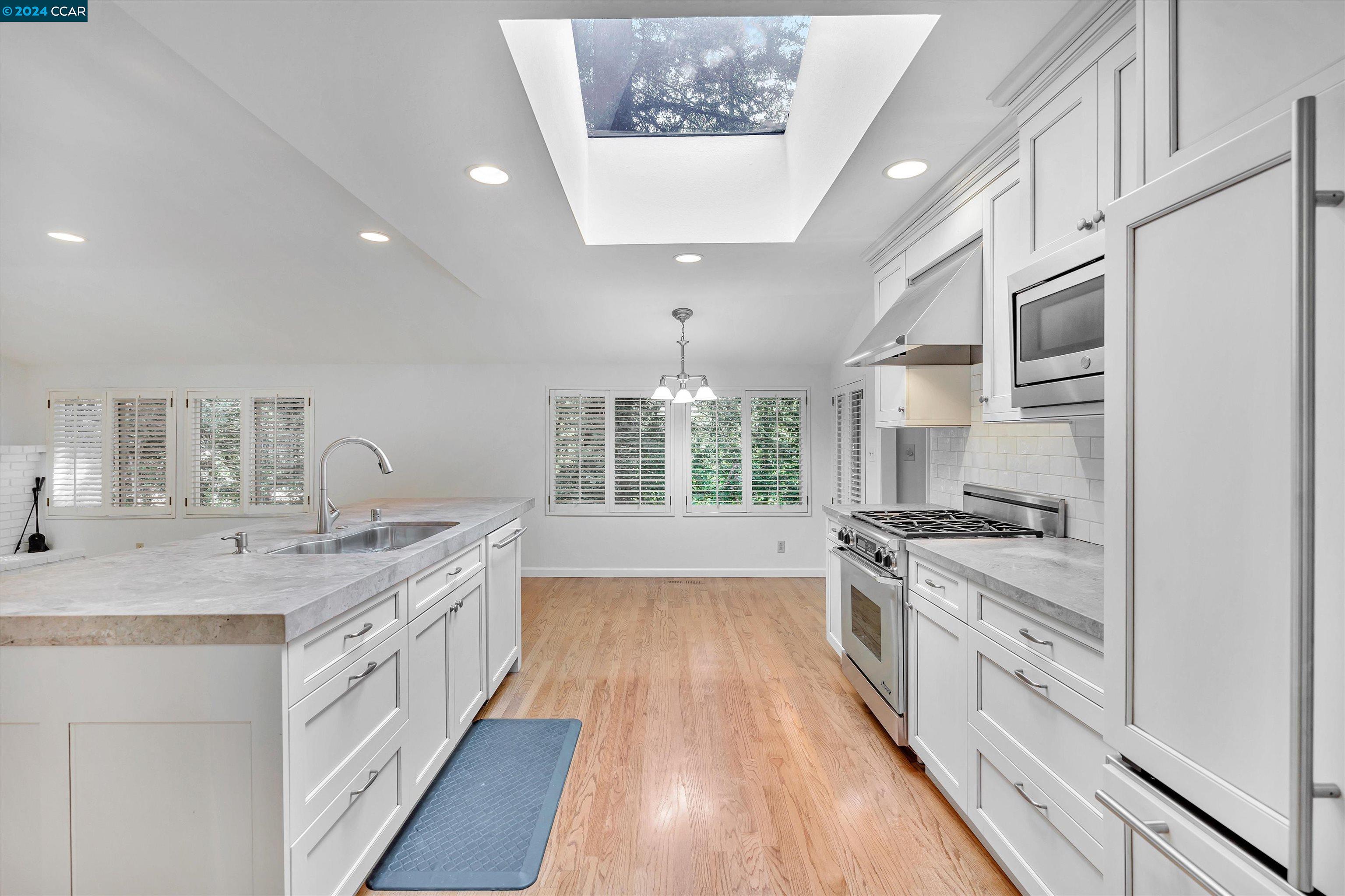 4105 Happy Valley Road Lafayette, CA 94549 - Photo 10 of 30 a large white kitchen with a stove top oven a sink a chimney wooden floor and cabinets