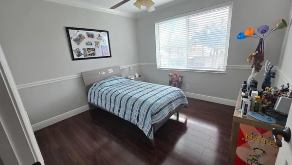 a bedroom with a bed painting on wall and a window