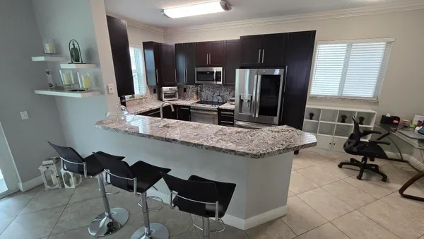 a kitchen with granite countertop kitchen island stainless steel appliances a sink counter top space and a window