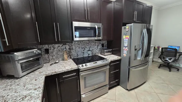 a kitchen with granite countertop a refrigerator stove and microwave