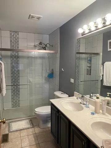 a bathroom with a double vanity sink toilet and shower