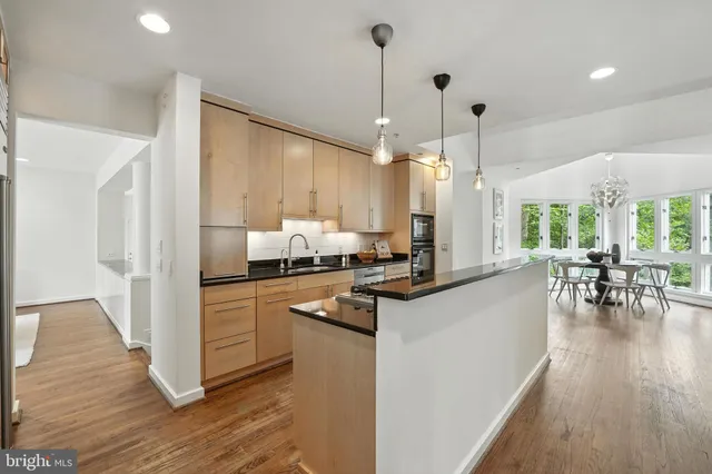a kitchen with stainless steel appliances kitchen island granite countertop a refrigerator a stove and a wooden floors
