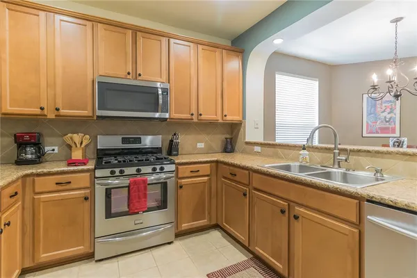 a kitchen with stainless steel appliances granite countertop a stove a sink and a microwave