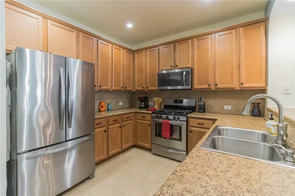 a kitchen with stainless steel appliances granite countertop a refrigerator stove top oven a sink and dishwasher