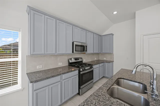 a kitchen with granite countertop a sink stainless steel appliances and cabinets