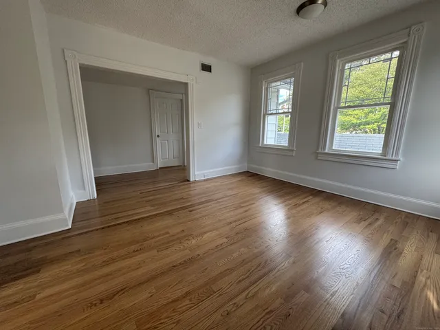 a view of an empty room with wooden floor and a window