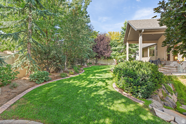 552 East Johns Way Sandy, UT 84070 - Photo 62 of 67 Expansive lawn with defined brick edging, mature trees, and a covered patio with dark railings