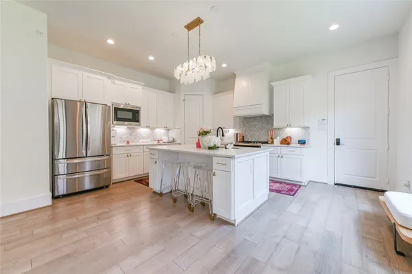 a kitchen with refrigerator a stove a sink and dishwasher with wooden floor