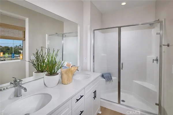 a bathroom with a granite countertop sink a mirror a potted plant and a shower