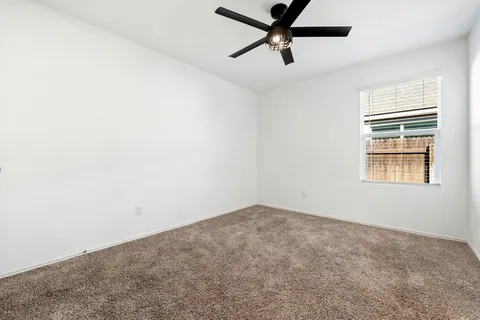 an empty room with a window and a fan