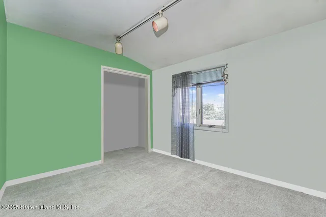 a view of an empty room with closet and windows