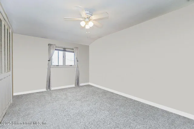 an empty room with windows and ceiling fan