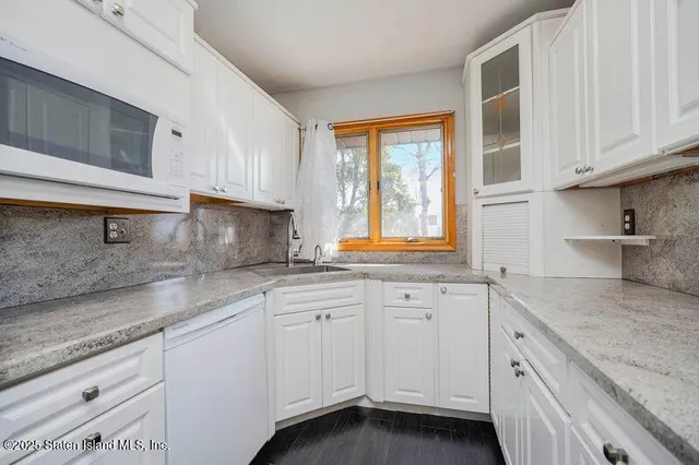 a kitchen with granite countertop white cabinets and a sink