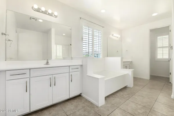 a spacious bathroom with a double vanity sink a mirror and a bathtub