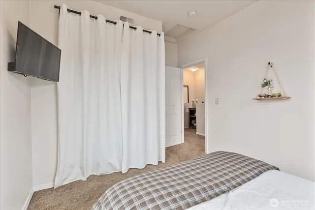 a bedroom with a bed and a flat tv screen on dresser